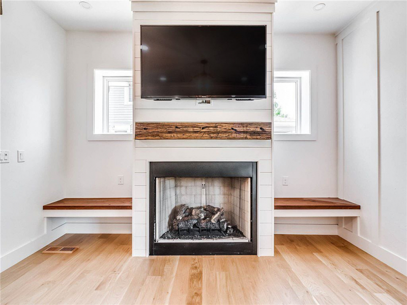 Fireplace with wooden mantle and additional seating and storage on either side