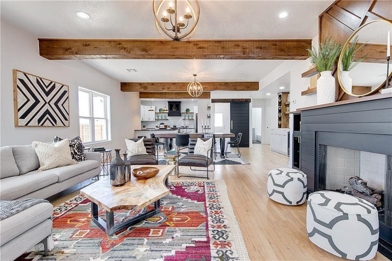 Living area with gray fireplace, rustic farmhouse decor, and wood support beams