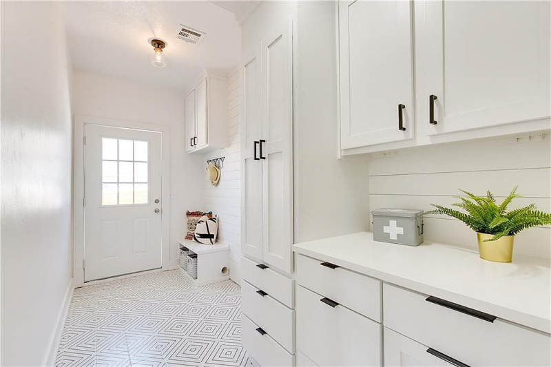 White laundry room with cabinets and storage
