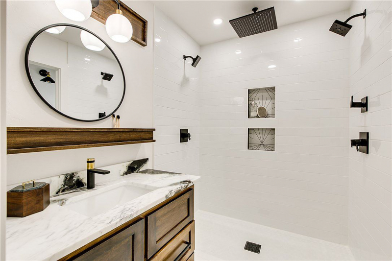 White tile bathroom with dark cabinets and wood accents, black hardware