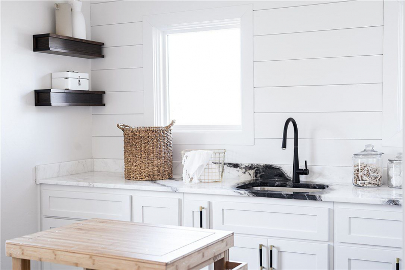 Laundry room with sink, white shiplap, and black hardware