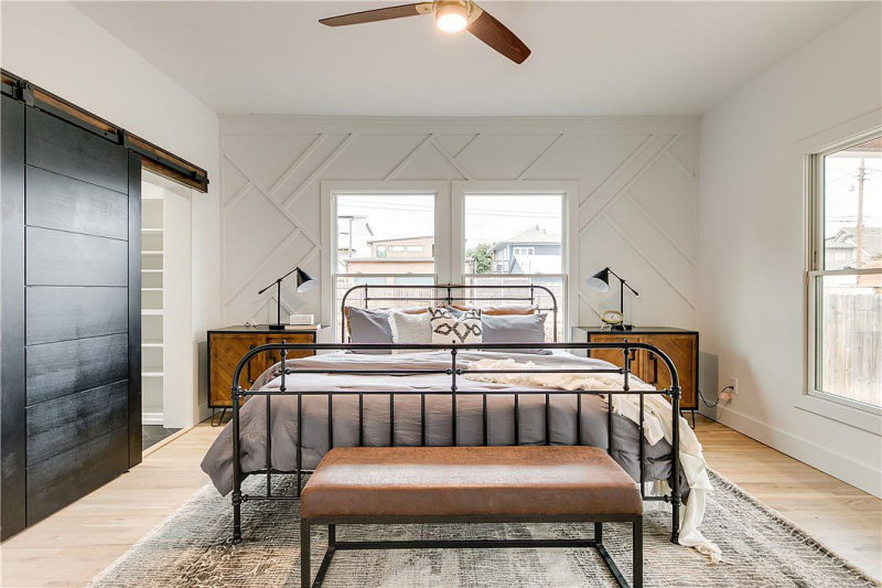 Bedroom with wood panel accent wall, industrial bedframe, and wooden end tables