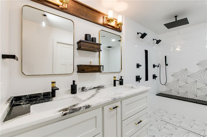 Double vanity with quartz countertop, white cabinets, gold hardware, and wood accent light fixtures