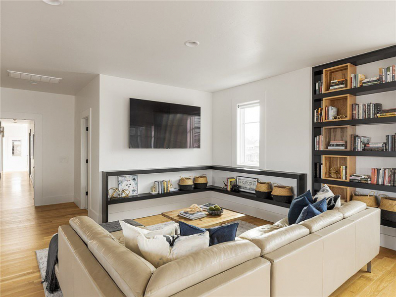 Secondary living area with tan couch and built-in bookshelves