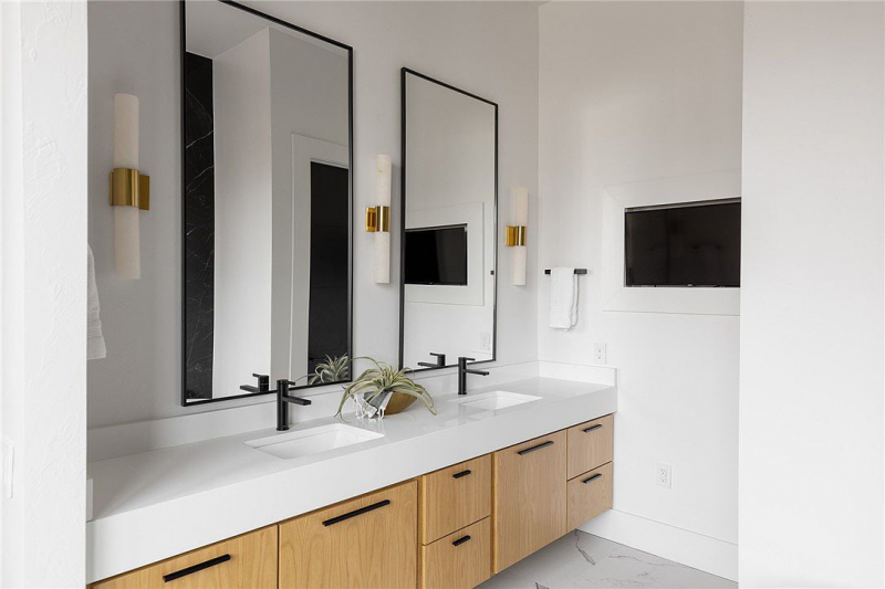 Modern bathroom with double vanity, white marble counters, and light wood cabinets