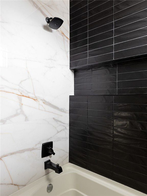 Bathtub with black subway tile accent wall