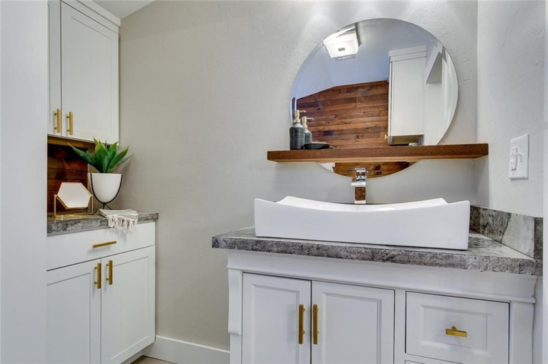 Bathroom with circular mirror and wooden shelf