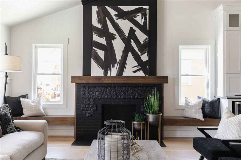 Black fireplace with wooden mantle and modern art