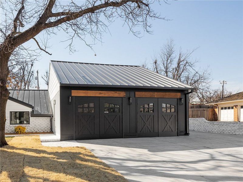 Black garage with black metal roof and wood accent